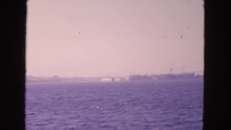 Soft 8mm San Francisco Bay frame with purple water, hazy shore, and a small white vessel near the horizon.