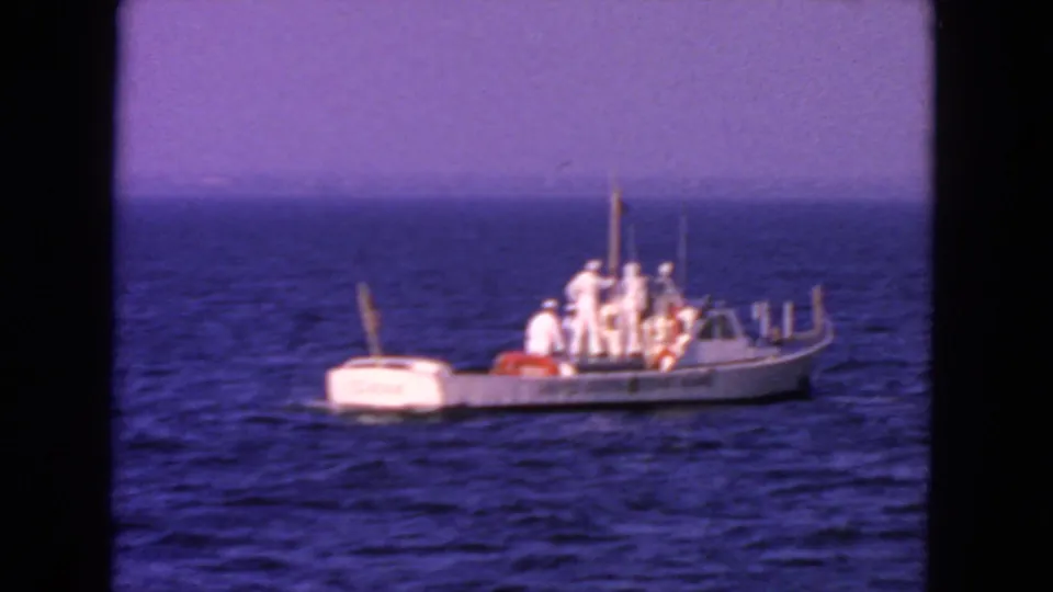 A white Coast Guard vessel with several uniformed crew members appears broadside on the water in 1963 San Francisco footage.