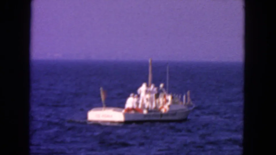 The small Coast Guard-marked boat moves farther across the ocean, with crew still visible on deck in a 1963 San Francisco home movie frame.