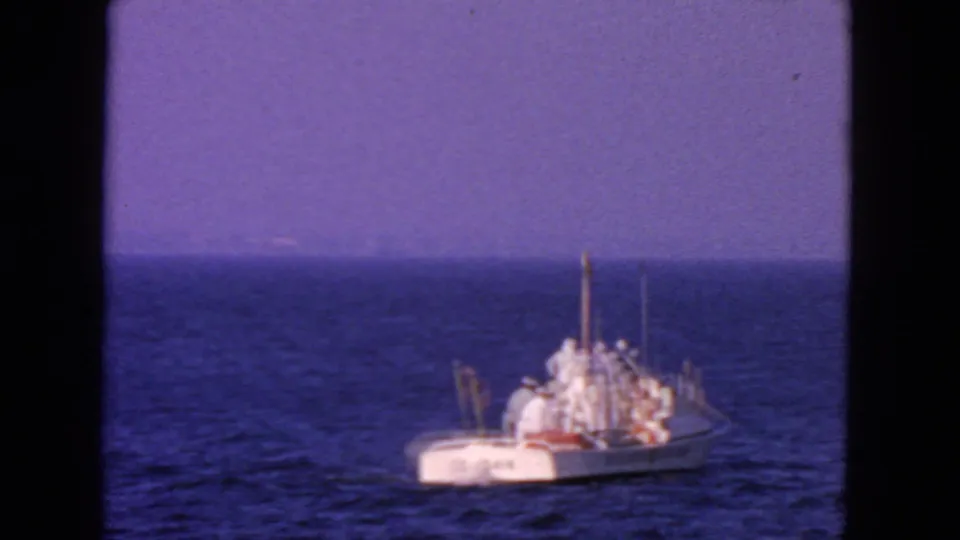 1963 San Francisco-area 8mm frame showing a small white Coast Guard boat with crew on open blue water.