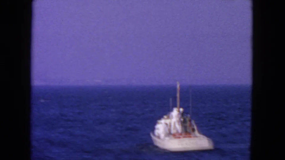 8mm home-movie frame of a white Coast Guard boat viewed from behind on San Francisco-area waters.