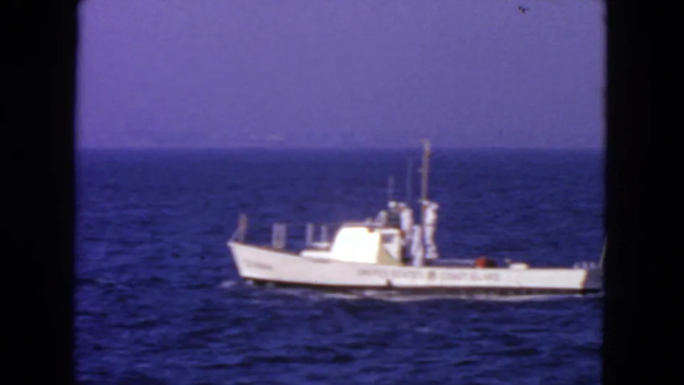 1963 San Francisco-area home-movie frame of a United States Coast Guard boat in profile on calm sea.