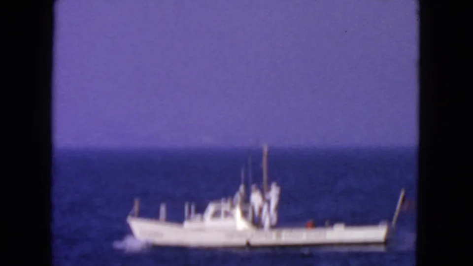 Soft 8mm frame from 1963 showing a white Coast Guard vessel traveling across blue water near San Francisco metadata location.
