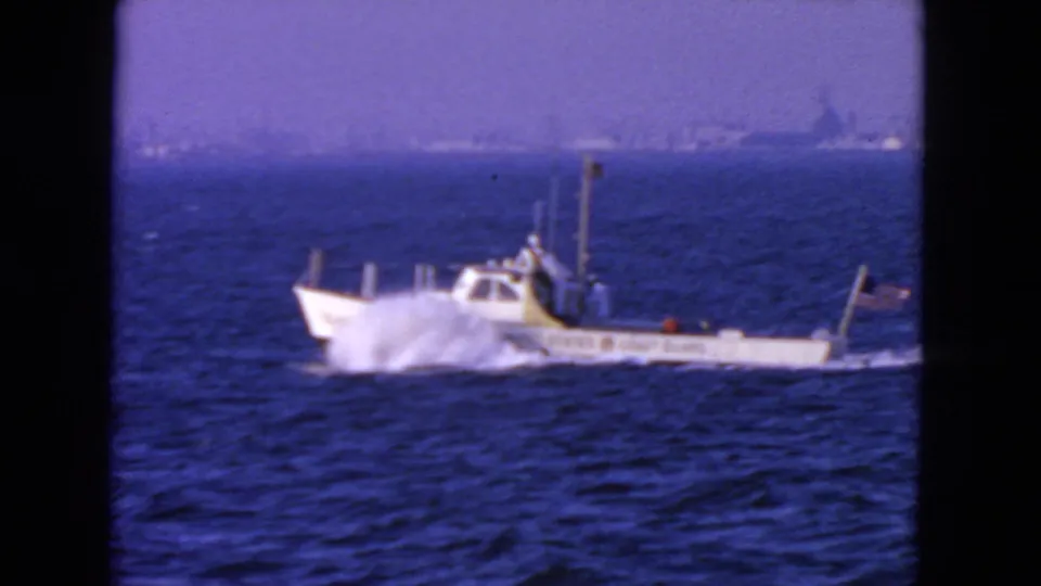 A 1963 San Francisco 8mm frame shows the small Coast Guard boat throwing spray on open water, with a faint distant shoreline.