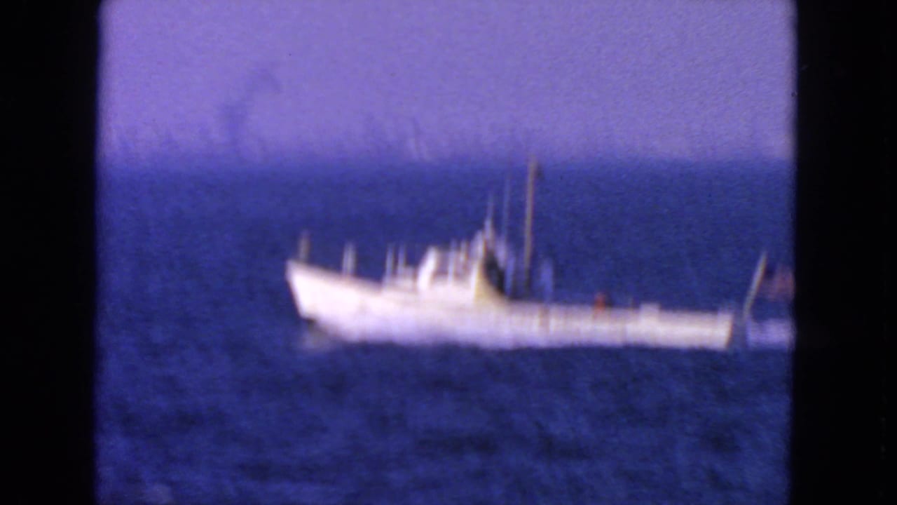White boat blurred on dark blue water with black film borders.