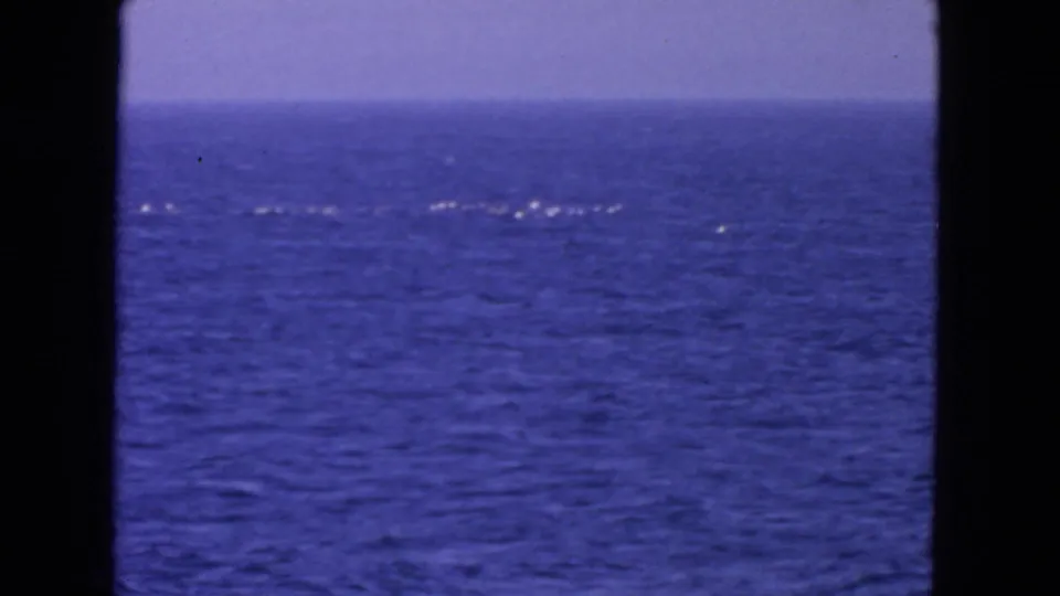 1963 8mm home-movie frame of open water near San Francisco, with a band of white foam crossing the blue ocean.