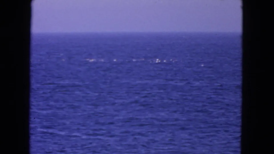 1963 8mm San Francisco-area ocean scene with scattered white foam, blue water, pale horizon, and dark frame edges.