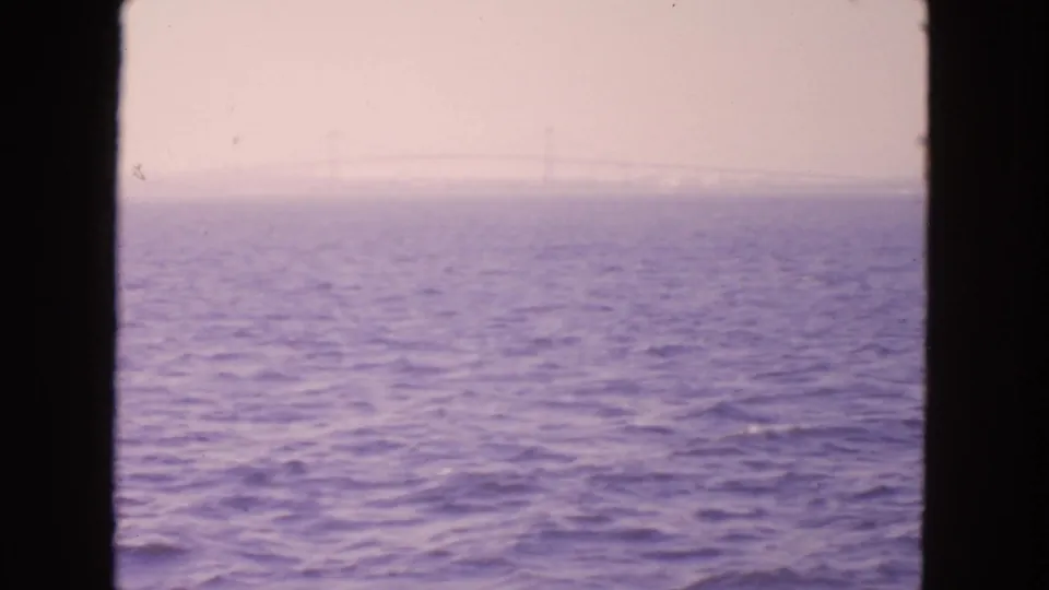 Hazy 1963 San Francisco-area waterfront view with rippled bay surface and faint distant structural lines through mist.