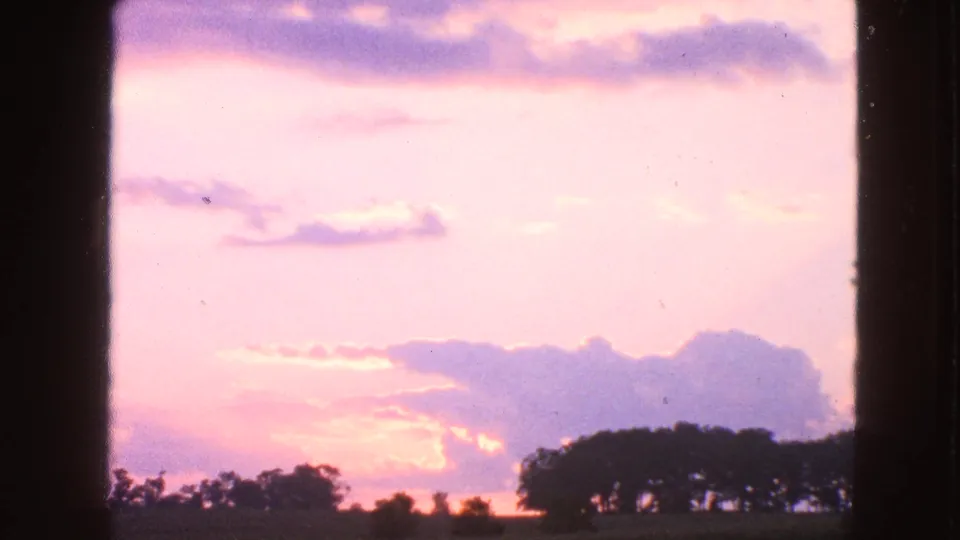 Walworth, Wisconsin 8mm sunset view with a pink sky, purple cloud bank, and silhouetted trees along the rural horizon.