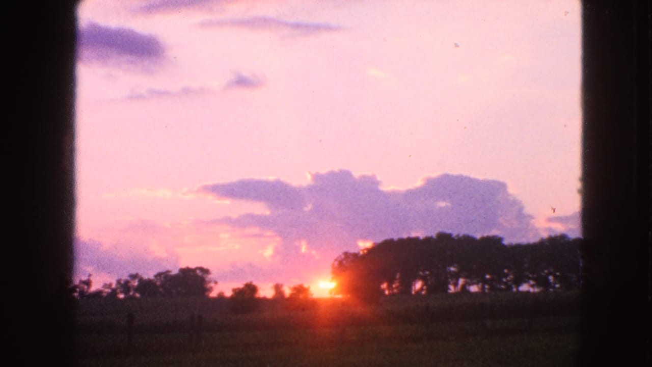 1963 Walworth, Wisconsin home-movie frame with the sun at the horizon, cloud bands, distant trees, and dark side framing.