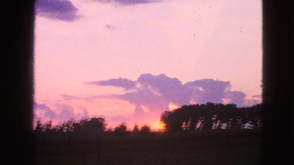 1963 Walworth, Wisconsin 8mm sunset frame with purple clouds, a glowing horizon, and trees in silhouette.