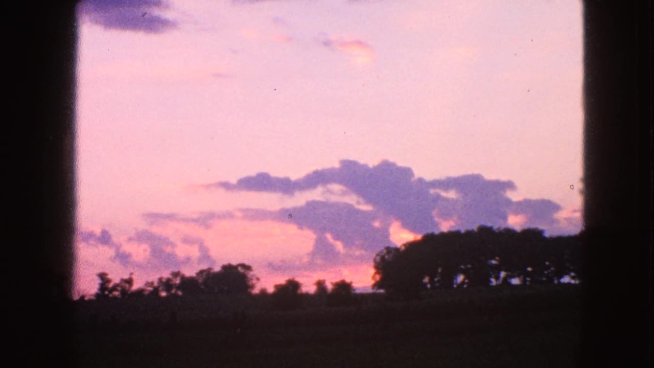 1963 Walworth, Wisconsin 8mm view of a pastel dusk sky with cloud banks over a dark treeline and farmland horizon.