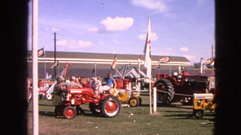 A red tractor stands in the foreground while visitors gather around other machinery at the Walworth tractor show.