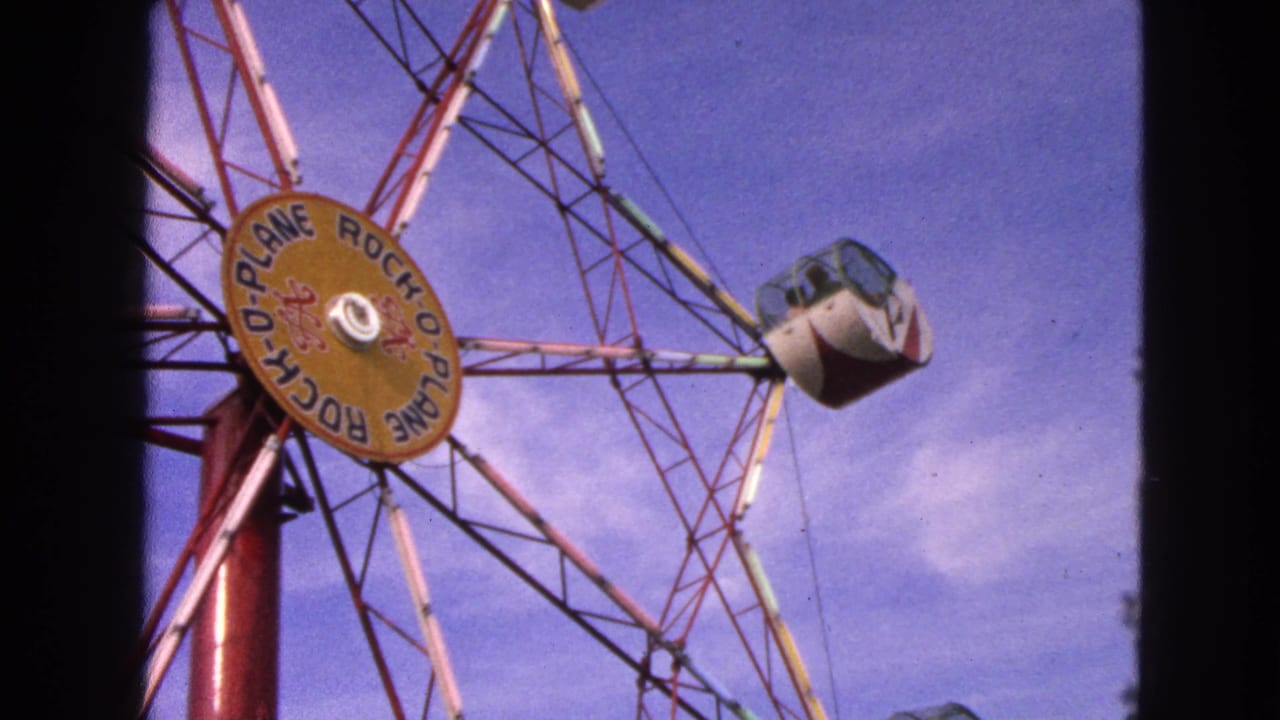 Rock-O-Plane amusement ride hub and enclosed cab against a blue sky.
