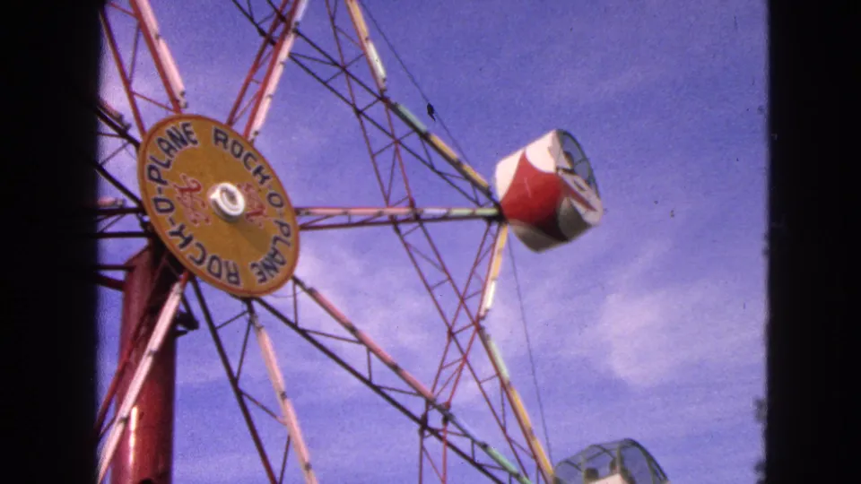 1963 Walworth, Wisconsin frame of the Rock-O-Plane ride with its yellow hub sign and red and white cab rotating overhead.