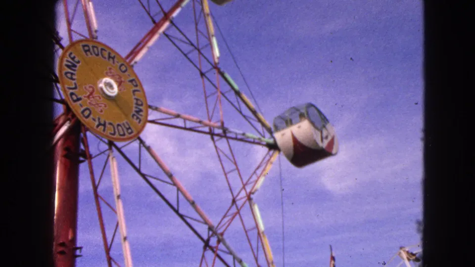 1963 Walworth, Wisconsin frame showing the Rock-O-Plane ride from below, with its hub sign, red tower, and enclosed cab in view.