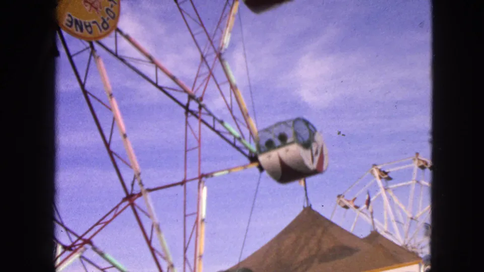 A 1963 home-movie view shows the Rock-O-Plane wheel above a tent roof, with another amusement structure in the background.