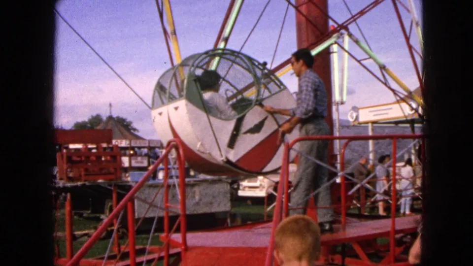 In Walworth, Wisconsin, an attendant appears to check a Rock-O-Plane gondola while visitors stand near the platform.