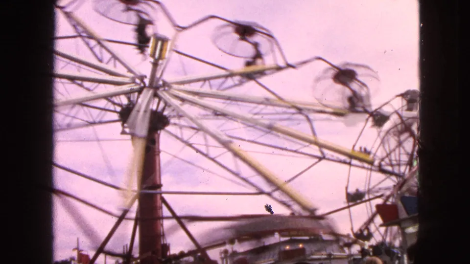 1963 Walworth, Wisconsin frame showing the Ferris wheel continuing at speed, with riders in small cars and fairground equipment visible near the lower edge.