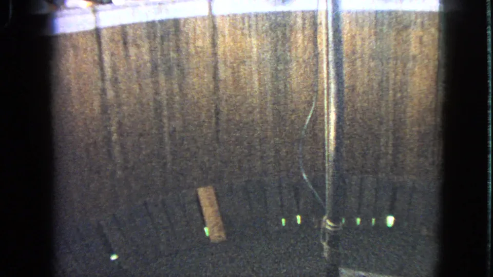 1963 Walworth, Wisconsin 8mm frame showing the racecourse surface, barrier, pole, loose plank, and green track-edge lights without a clear rider.