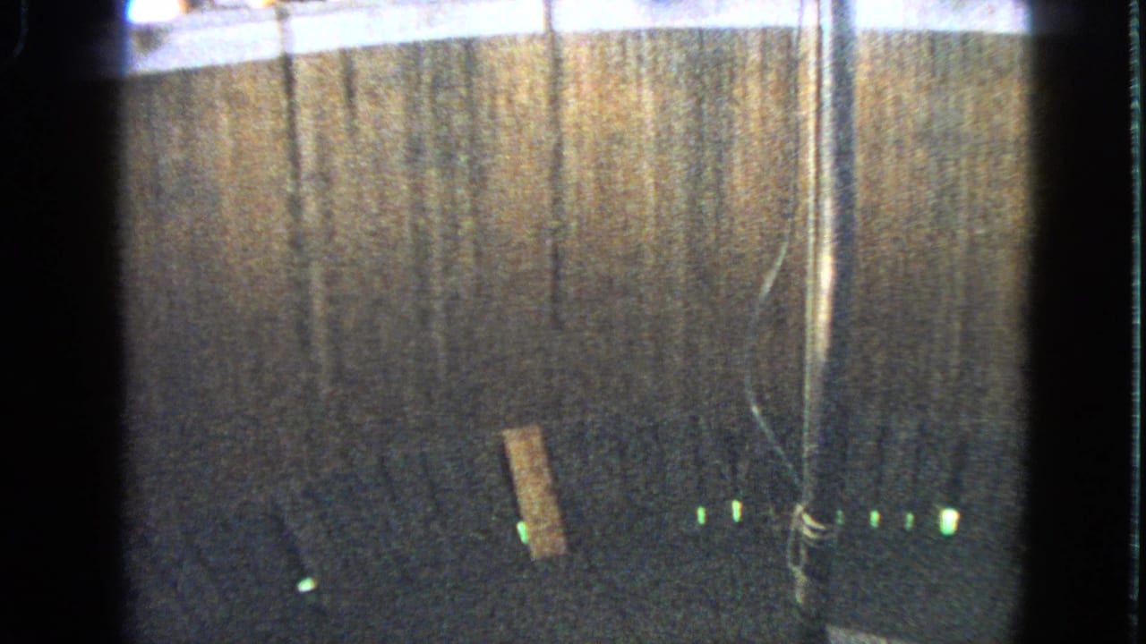 Wooden circular stunt wall with green base lights and a central pole, before the motorcycle enters frame.