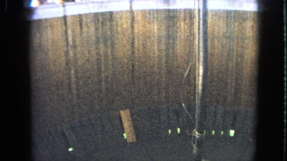 1963 Walworth home-movie frame showing the wooden stunt wall and interior lighting with the rider out of frame.