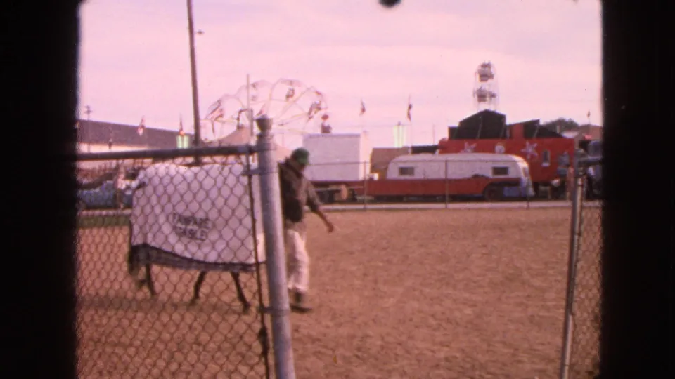 A covered horse marked with fair-stable style lettering passes through the Walworth fairground arena as a handler walks nearby.