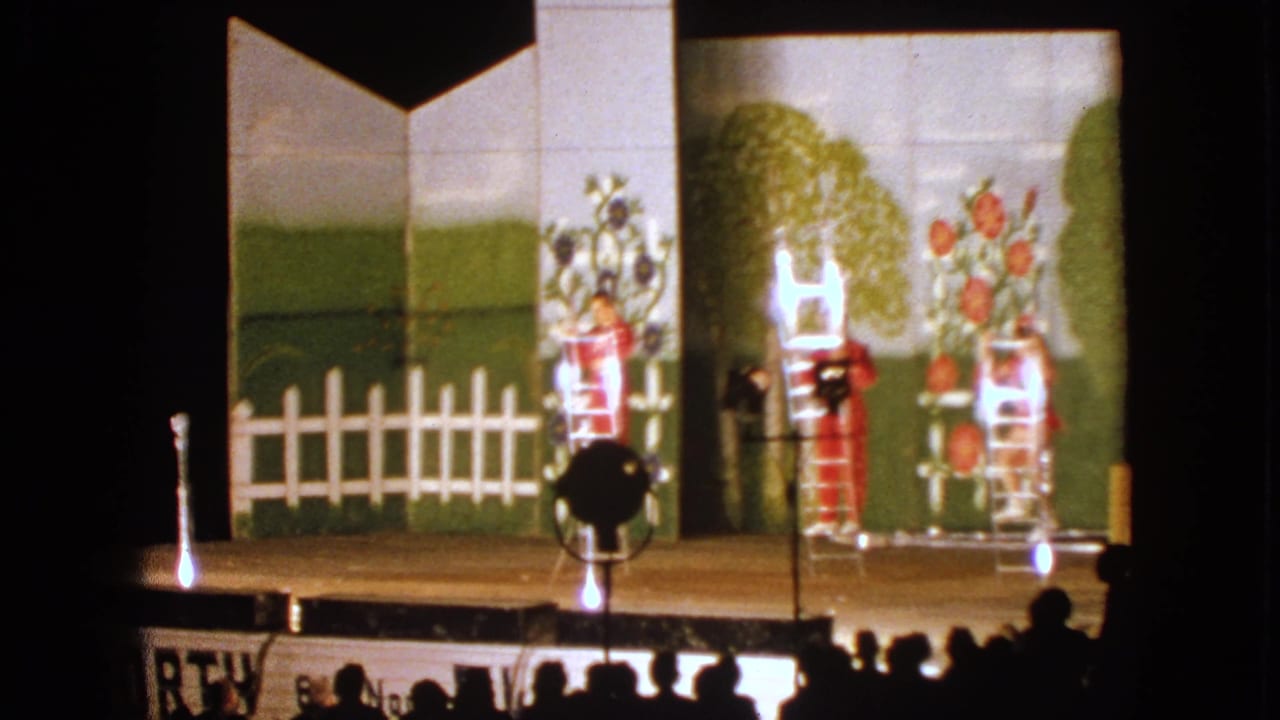 1963 Walworth stage scene with performers in red costumes positioned on ladders under bright stage lighting and audience silhouettes below.