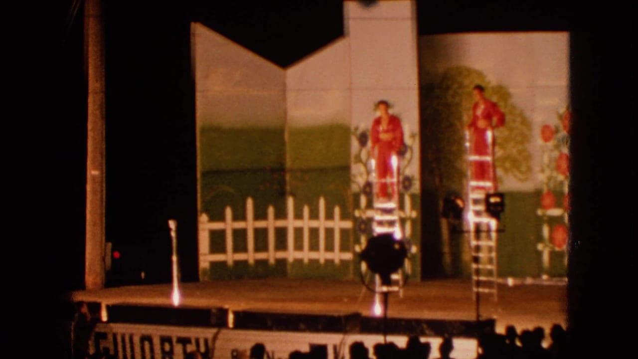 1963 Walworth, Wisconsin stage view with a red-clad performer elevated on a ladder beside spotlights and scenic flats.