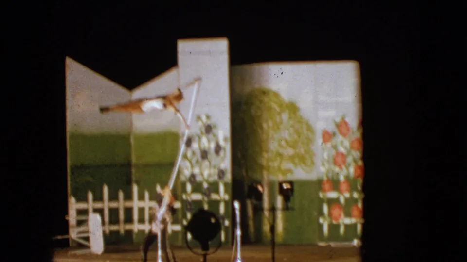 1963 Walworth, Wisconsin frame showing a young acrobat held sideways on a pole with an adult assistant beneath the painted set.