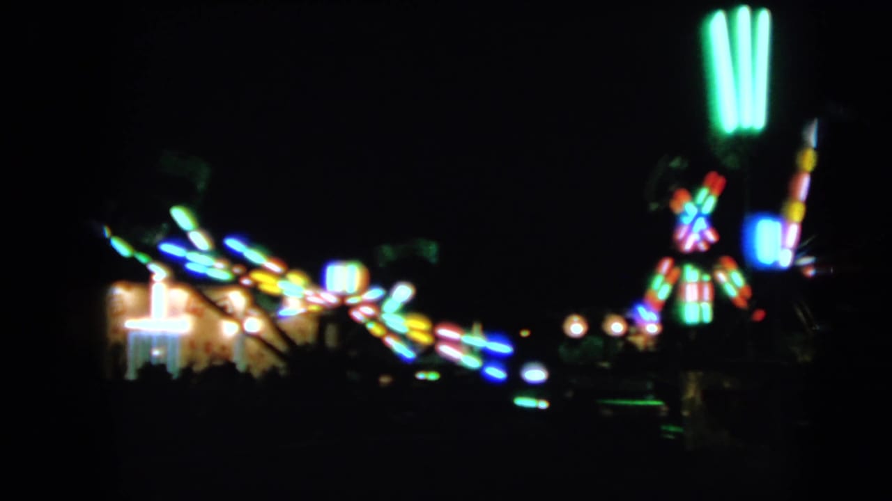Blurred colorful carnival ride lights against a dark night sky.