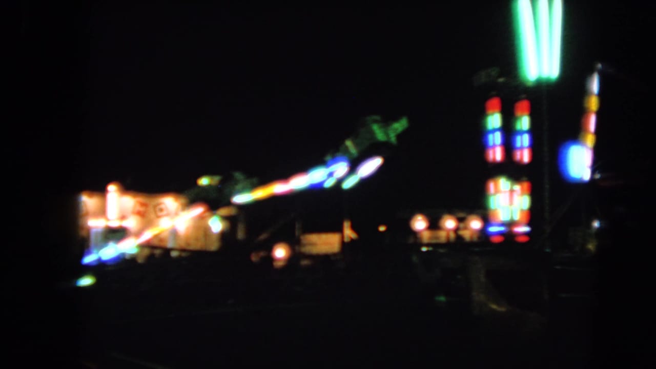 1963 Walworth, Wisconsin fair footage showing soft, colorful ride lights glowing across a dark midway.