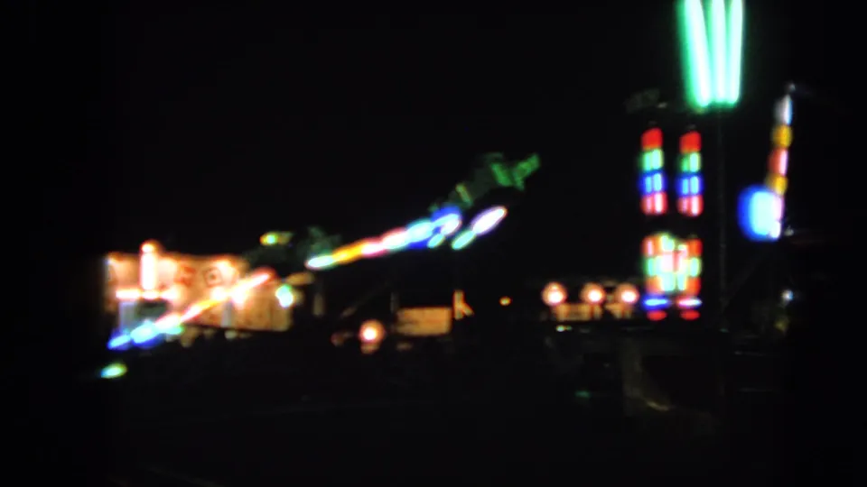 1963 Walworth, Wisconsin fair footage showing soft, colorful ride lights glowing across a dark midway.