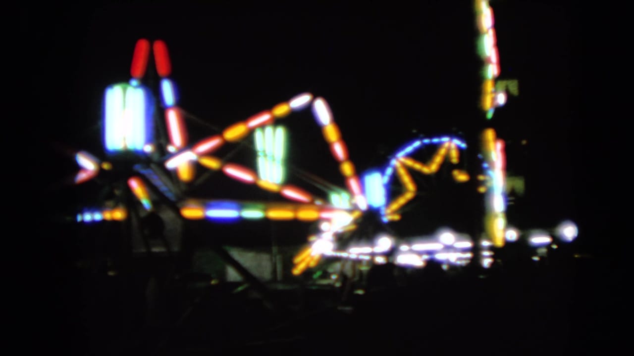 Blurred colorful carnival ride lights against a dark night sky.