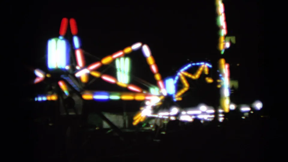 Soft 8mm view of colorful nighttime carnival ride lights in Walworth, Wisconsin, from 1963 metadata.