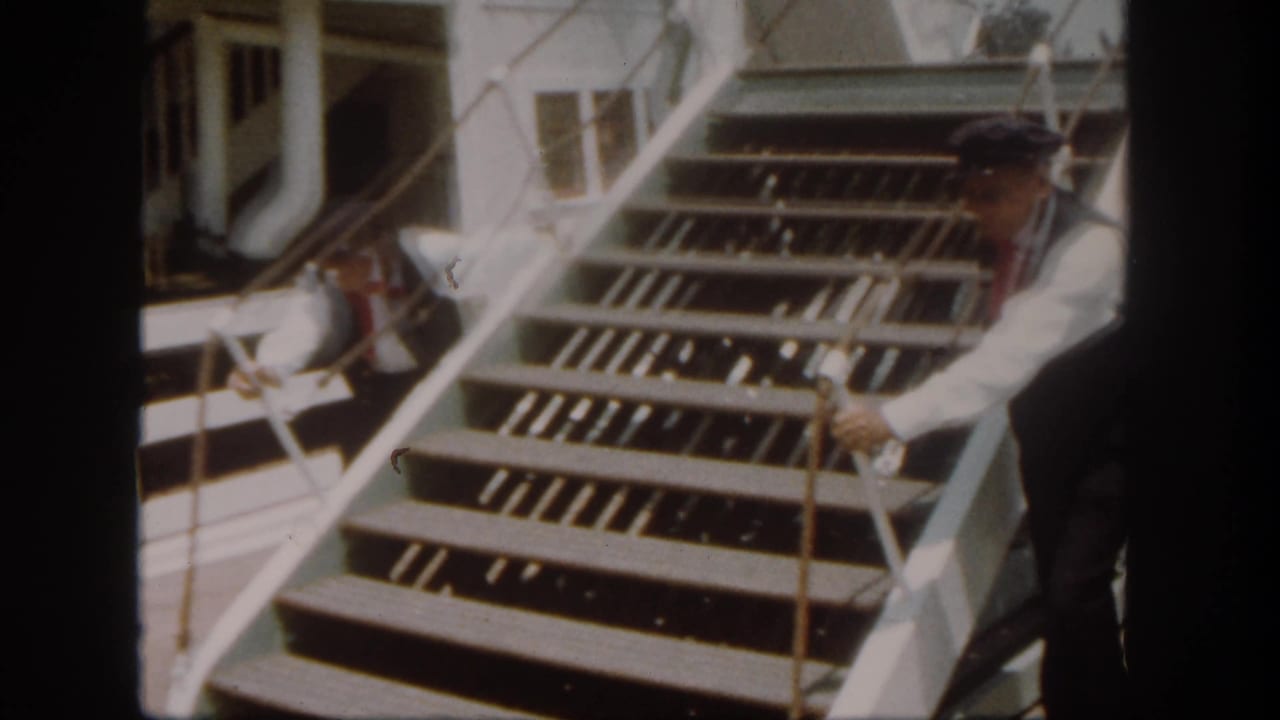 A uniformed crew member works beside the riverboat gangway stairs during boarding at Disneyland California, supported by the 1962 metadata.