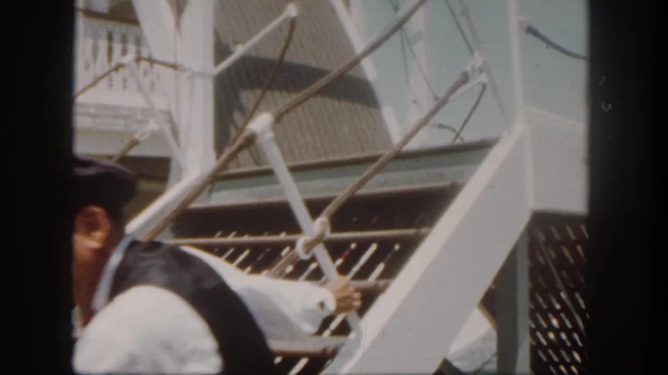 A close, soft 8mm view shows a crew member beside the riverboat stairs and white railing during the boarding sequence.