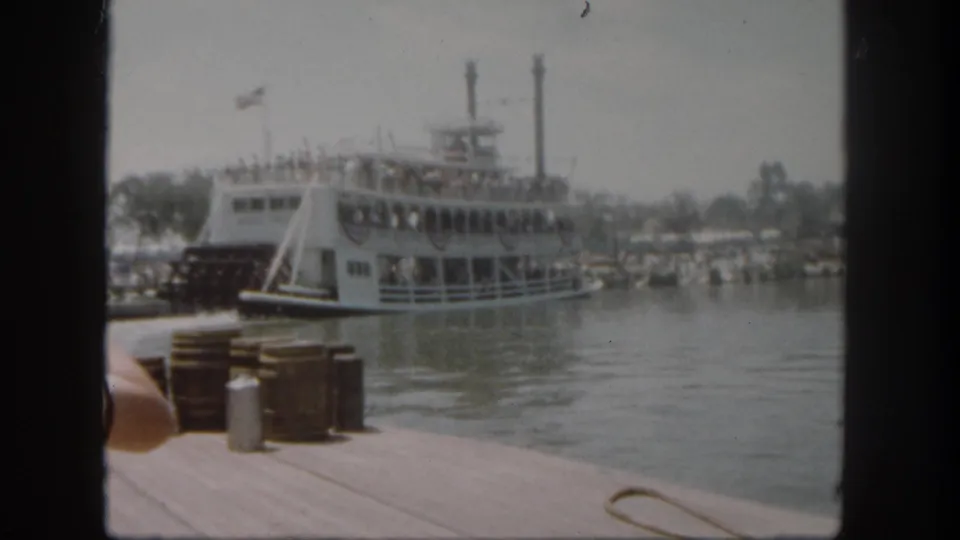 The Mark Twain Riverboat is farther out on the water at Disneyland, with dock barrels and a metal can still visible in the foreground.