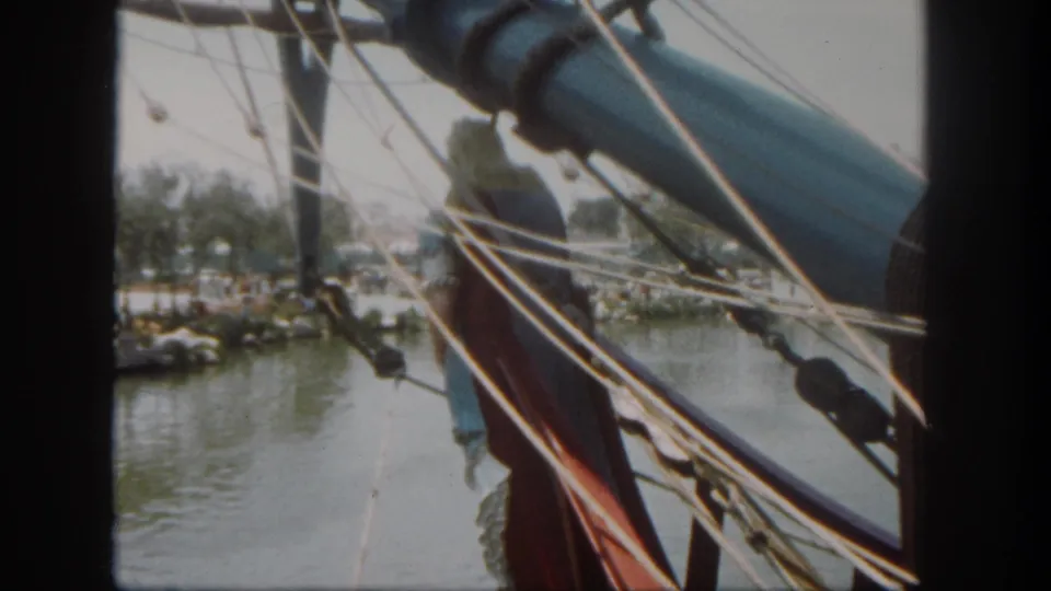 A handheld Disneyland waterfront view is partly blocked by ropes and rigging, suggesting the camera is on another boat or attraction.