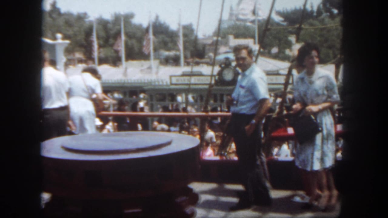 Guests stand on a riverboat deck near a large round bollard and harbor railing.
