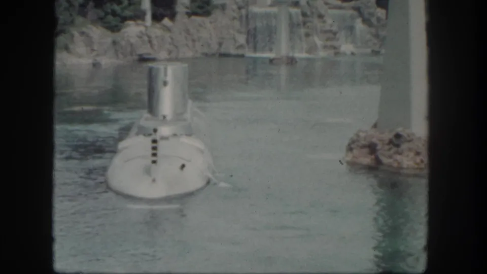 The Disneyland submarine appears slightly farther along the lagoon, framed by rock scenery, falling water, and a vertical white pillar.