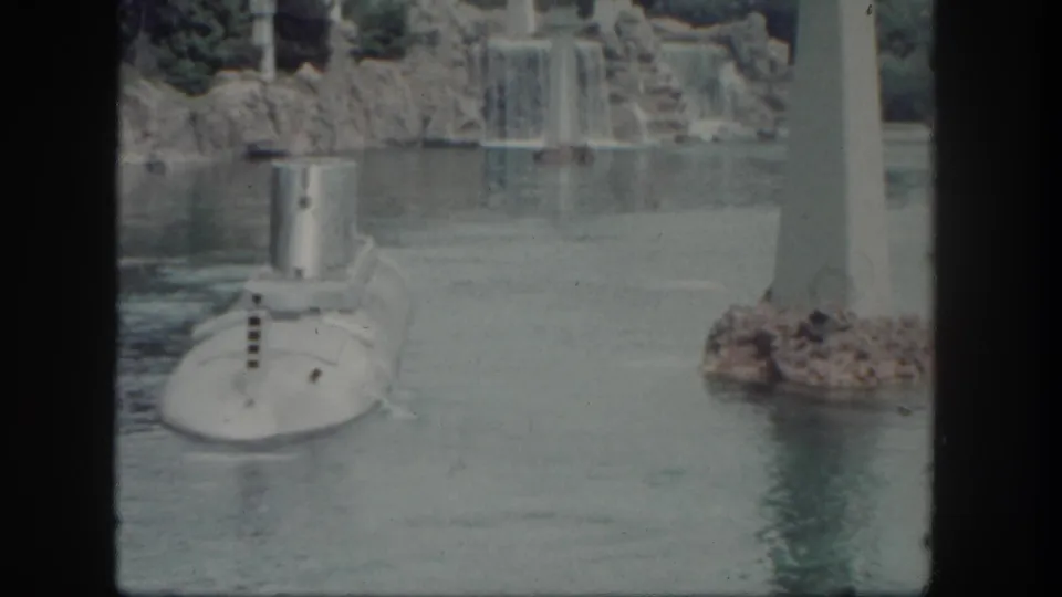 A soft 8mm view of the Disneyland submarine attraction, with the vehicle low in frame and waterfall scenery behind it.