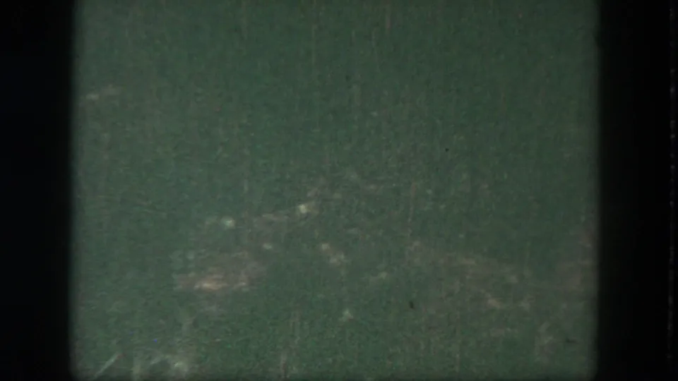 Final dim 1962 Disneyland frame showing greenish water, faint reflection patches, and dark 8mm frame edges.