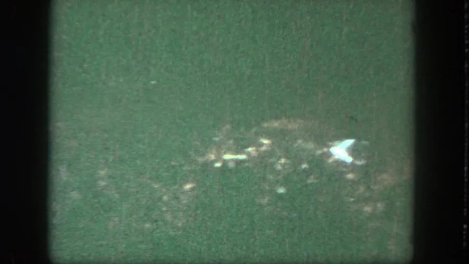Opening 8mm frame with dark gate edges, green color cast, and a barely visible outdoor amusement park view.