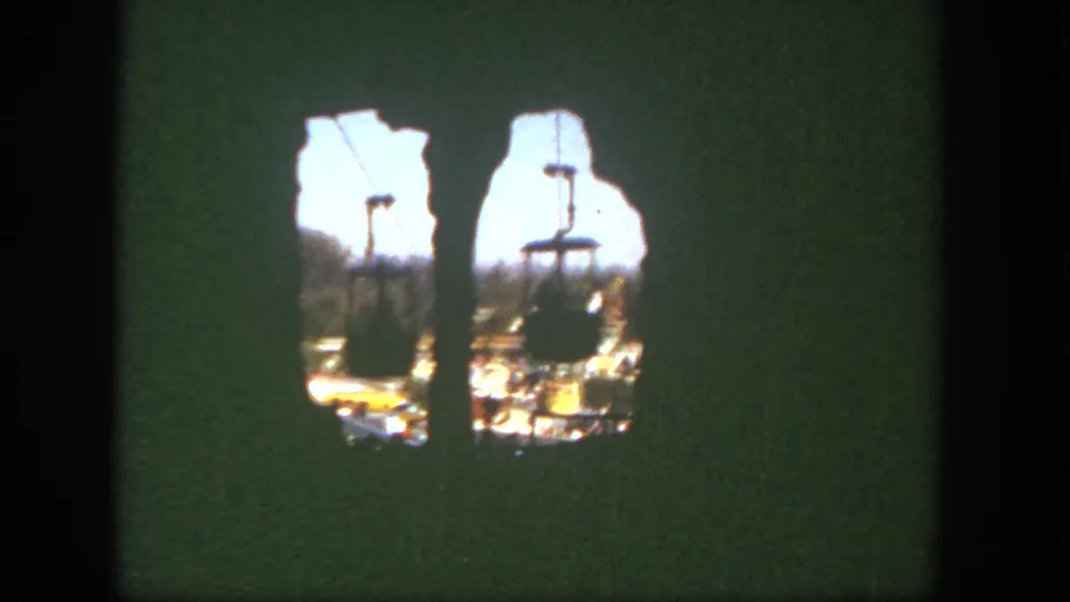 End frame from the 8mm clip, with most of the view darkened and small openings showing cable cars moving over the park.