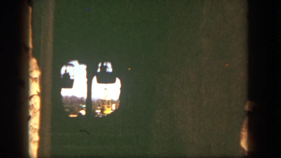 Late frame of the 1962 Disneyland cable car view, with gondolas partially obscured by the rocky wall and film edge.