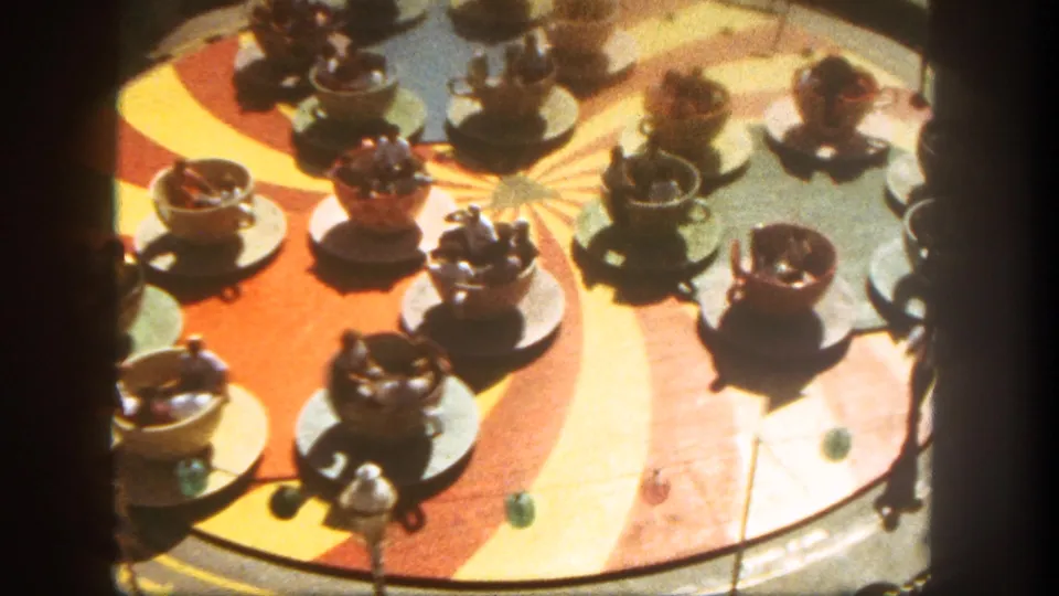 1962 Disneyland Mad Tea Party teacups on a colorful sunburst platform, seen from above with riders inside several cups.