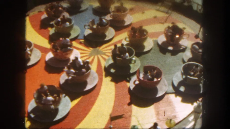 Overhead visitor view of Disneyland's Mad Tea Party ride in 1962, showing several teacups, saucers, riders, and the painted sunburst floor.