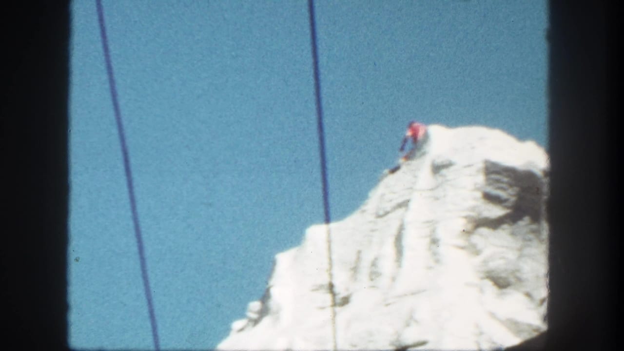 1962 Disneyland frame of the simulated snow-covered peak, with cableway lines visible and a small red-clad figure near the top.