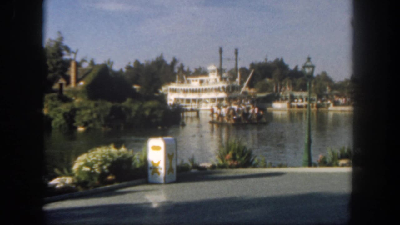 White steamboat on a park waterway seen past dark window edges.